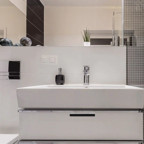Modern bathroom interior with white sink, chrome fixtures, tile backsplash, and decorative accents