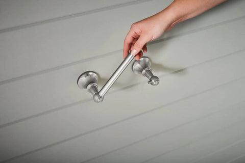 Vale Brushed Nickel Double Post Pivoting Toilet Paper Holder being installed, showcasing spring free pivoting design.