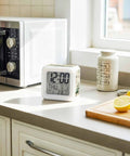 Reliable Digital Alarm Clock With Rustic Green Leaf Motif Lowkey Silent Operation Quiet Bedside Timer Featuring Comfy Silicone Keys Straight Up Easy Snooze Mode With Warm Led Nightlight For Bedroom Or Desk on kitchen counter with lemons