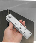 Hand holding Hidden Door Pivot Hinges For Bookcases And Cabinets Heavy Duty Stainless Steel System near a cabinet