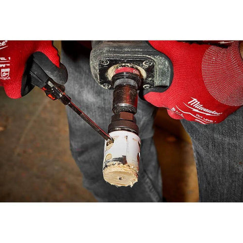 Milwaukee Bi-Metal Hole Saw, 3-1/2 in, mounted on drill chuck cutting PVC pipe; red Milwaukee gloves worn