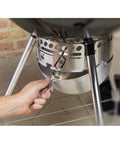 Hand using the One Touch Cleaning System on the Original Kettle Premium Charcoal Grill 22 Inch Black Outdoor BBQ Grill.