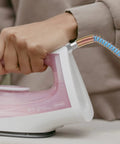 Person using a PTFE High Temperature Steam Hose For Steam Irons High Pressure Tube Lightweight And Durable Steam Line For Ironing Flexible Hose For Garment Care Easy Connect Pro Grade Home Use connected to a pink iron.