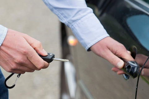 Person using retractable keychain to unlock car door, showcasing Five Pack Retractable Keychain Badge Holders With Steel Wire Reel Clip Durable ID Badge Reels For Lanyards Heavy Duty Retractable Reels Black Ideal For Office School Security Access.