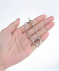 Hand holding a 2x45mm brooch-shaped cotter pin from the 8 Pack Brooch Shape Cotter Pins With Quick Lock Fasteners set for outdoor use.
