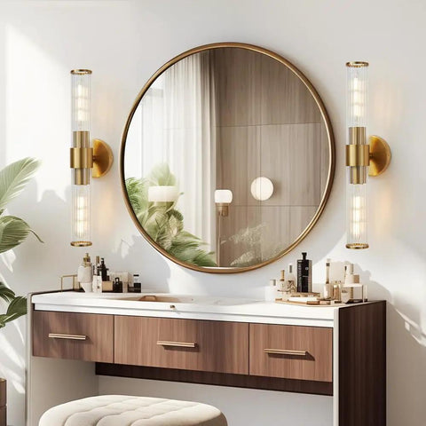 Luxurious bathroom setup with gold wall sconces beside round mirror, over wooden vanity.