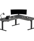 Electric Height Adjustable L Shaped Corner Desk, Massive 72 By 60 Workspace Platform with gray oak finish and dual monitors.
