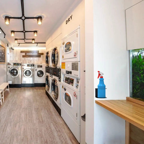 Wall Mounted Spray Bottle Holder Rack For Garage And Home holds a blue spray bottle in a laundry room setup.