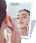 Woman using Your Go To LED Travel Vanity Mirror With 3 Color Ring Light For Consistent Lighting Dimmable Brightness Handheld Portable Design Built In Touch Sensor Rechargeable Micro USB White Finish On The Go Grooming.