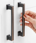 10 Pack 5 Inch Hole Centers Oil Rubbed Bronze Cabinet Pulls being installed on white cabinet doors