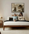 Premium King Solid Wood Bed Frame With Classic Japanese Joinery And Reinforced Wooden Slats For Rock Solid Support That Ditches The Box Spring Requirement While Providing Hassle Free Assembly For Your Cozy Bedroom Vibe In Rich Walnut with a couple relaxing in a cozy bedroom.