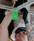 Contractor using Tough As Nails 12V Max Cordless Self Leveling Green Beam Laser Kit for ceiling alignment with green laser target.