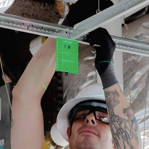 Contractor using Tough As Nails 12V Max Cordless Self Leveling Green Beam Laser Kit for ceiling alignment with green laser target.