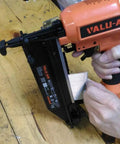 Person using a pneumatic nail gun to load Pro Grade Galvanized Finish Nails 16 Gauge 1 Inch Straight Head Built Tough For Pneumatic Or Cordless Nailer Guns Solid 2500 Count Box For Fine Woodworking And Trim Installations.