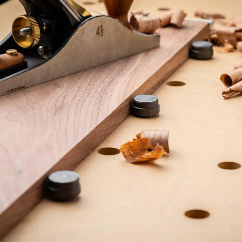 Wood plane on workbench with Spaced Dog Hole Router Template for precise holes and bench tools like dogs and cookies.
