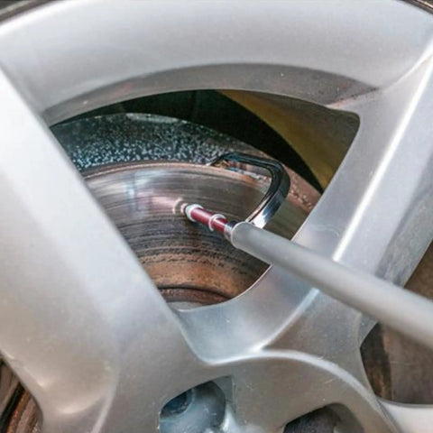 Brake Disc Thickness Measurement Verniers Caliper measuring brake disc through car wheel, with a visible aluminum body and gauge.