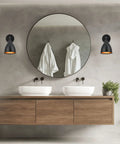 Set Of 2 Matte Black Bell Shade Wall Sconces With Switch, illuminating a modern bathroom with double sinks and round mirror.
