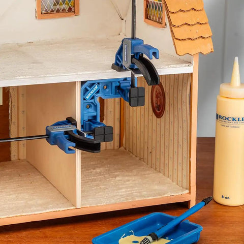 Clamp It Mini Assembly Squares 4 Pack For 90 Degree Corner Clamps In Woodworking used in dollhouse setup with glue bottle visible.