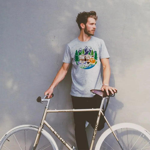 Man wearing gray t-shirt featuring Camping Stencil For Painting 11.8 Inch Square Reusable RV Mountain Tree Template, holding bicycle