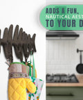 Heavy Duty Cast Iron Wall Hook Rack Featuring A Badass Fish Bone Skeleton Layout With Four Chunky Rustic Hooks holding kitchen mitts.