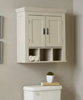 Cream bathroom wall cabinet with two doors and black handles, displayed above a toilet, featuring decorative wall art on the side.