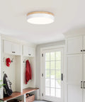 Modern round ceiling light fixture in a bright mudroom with white cabinetry and wood accents.