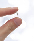 100 Pack Stainless Steel Eye Hooks 0.66 Inch Silver Heavy Duty Eye Screws held between fingers for DIY projects