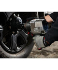 Badass 3/4 Inch Drive Air Impact Wrench Delivering Straight Up 1100 Ft Lbs Max Torque in use on a black wheel, featuring a pistol grip handle.