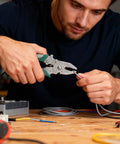 Man using Badass 12 In 1 Foldable Wire Stripper And Cable Cutter Pliers to strip wire on a workbench.