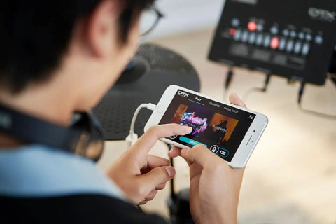User controlling the DTX-PRO Electronic Drum Trigger Module With 70 Premium Customizable Kits via smartphone app interface.
