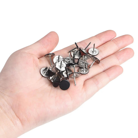 Top Shelf Decorative Upholstery Tack Nails Featuring A Sleek Black Carbon Steel Build Engineered To Give Drab Couches A Serious Glow Up Arrives As A Bulletproof 150 Piece Kit For Lazy Sunday Renovations in a hand with assorted black tacks.