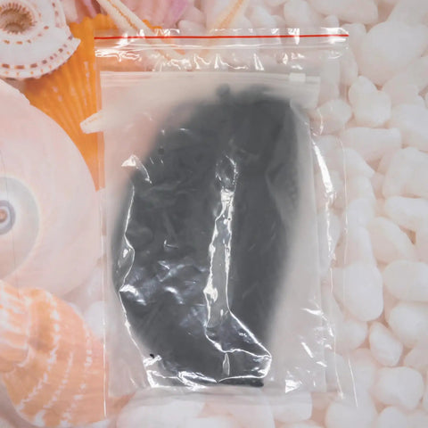 Black Golf Ball Storage Bag Portable Drawstring Pouch in packaging, polyester nylon mesh material behind seashell background