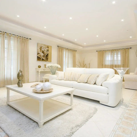 Living room with 4 Pack 5 to 6 Inch LED Recessed Can Lights, modern white decor, white sofa, high ceiling, ample daylight.
