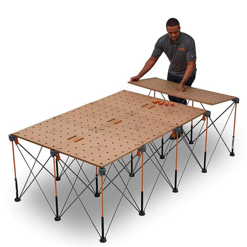 Man assembling Centipede Workbench Tabletop For On The Go Portable Centipede Stand Saw Horses 24 Inch By 48 Inch Wood Top With Dog Holes