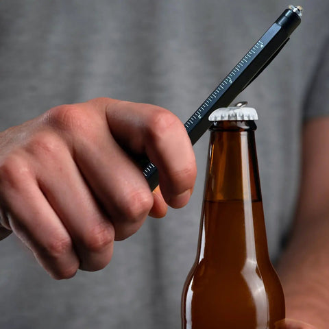 Person using Two Piece Multitool Pen Set For Everyday Carry With Nine In One Steel Pen And Six In One Aluminum Pen Includes Gift Box Bonus Batteries to open a bottle