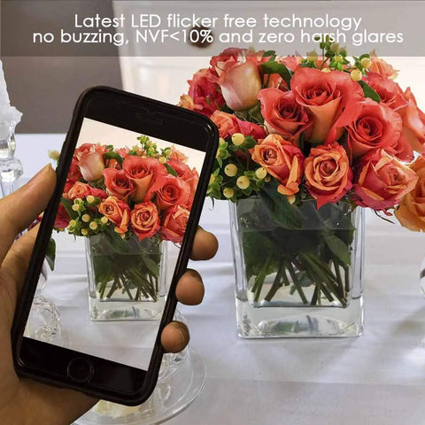 Smartphone capturing a photo of a vibrant floral arrangement in a clear glass vase with LED lighting in background.