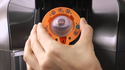 Person using 2.0 Needle Cleaning Tool For Keurig 2.0 Brewers Maintenance Accessory For Clearing Needle Block No Fuss Flush Dried Coffee Debris Compatible Only With Keurig 2.0 Brand New In Box Orange Color