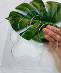 No Sweat Paw Print Router Template Crafted From Durable Clear Acrylic For Hella Easy Wood Inlays held above a green leaf.