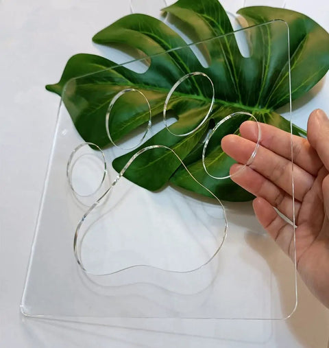 No Sweat Paw Print Router Template Crafted From Durable Clear Acrylic For Hella Easy Wood Inlays held above a green leaf.