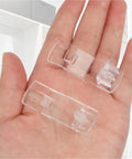 Clear Plastic Shelf Clips 40 Or 50 Piece Set Self Locking Cabinet Support Pegs for One Quarter Inch Holes resting on a hand