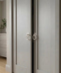 Large White Ring Bi-Fold Closet Door Pulls With Protective Base 1-3/5 Inch installed on wooden sliding doors in a modern setting.