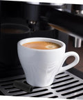 Two Pack Steam Wand Safety Guards For Coffee Machines Rubber Steam Pipe Cover next to espresso cup on machine tray