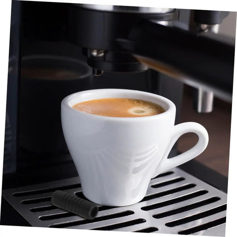 Two Pack Steam Wand Safety Guards For Coffee Machines Rubber Steam Pipe Cover next to espresso cup on machine tray