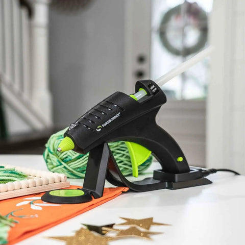 Cordless High Temperature Glue Gun 60W with standby base for craft projects shown with decorative items on table.