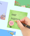 Green note from 9 Pads Cute Sticky Notes Set 3x3 Self Stick Notepads with 'KEEP FIGHTING' handwritten in black ink held by hand