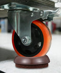 Close-up of a caster on a felt chair leg pad and caster cup set, protecting a hardwood floor from scratches.