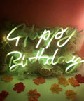 Lit LED Neon Sign Night Light For Wall Decor And Party Ideal For Bedroom Living Room Bar Wedding Home Birthday Christmas USB Powered 5V With Chain Light Modulator Energy Saving Acrylic Neon 16.1X11 Inches showing 'Happy Birthday' in green glow against a floral background