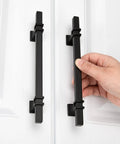 Person installing 25 Pack 5 Inch Matte Black Cabinet Pulls Zinc Alloy Dresser Handles on white cabinet doors.