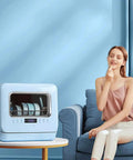 Pretty Slick Countertop Dishwasher Fully Automatic Stainless Steel With Six Place Settings LED Display And Delay Start Quick Connect Faucet Adapter Smooth Hassle Free Setup on a table in a modern living room.