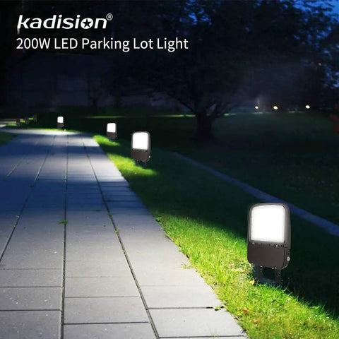 LED Parking Lot Light With 240W 200W And 150W Options illuminating a sidewalk at night with trees in the background.